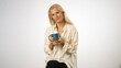 © Robert Peak - Portrait of elegant beautiful smiling happy blond mature woman holding cup drinking coffee or tea looking to the side on solid white background with copy space