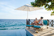 © Fokke Baarssen - Curacao, couple man and woman mid age relaxing by the swimming pool during a vacation in the Caribbean