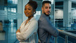 © Yuliia - Business portrait diverse coworkers two colleagues African American confident woman businesswoman and Arabian Indian man ethnic businessman in office posing for camera with crossed arms crossing hands