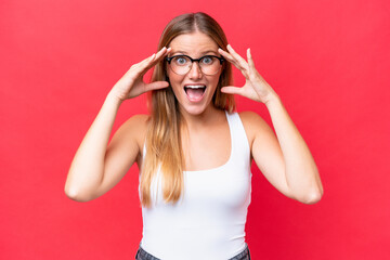 Wall Mural - Young beautiful woman isolated on red background with surprise expression