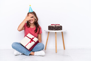 Young Russian girl celebrating a birthday sitting one the floor isolated on white background covering eyes by hands and smiling