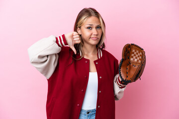 Wall Mural - Player Russian woman with baseball glove isolated on pink background showing thumb down with negative expression