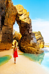 Wall Mural - Beautiful woman with red dress walking on famous cathedral beach in Galicia, Spain