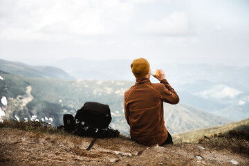 Wall Mural - A tourist drink water on the edge of a mountain peak. Foggy mountains on the background. Landscape photography