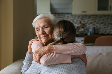 grandmother and granddaughter hugging in the living room. two adult women of different age. family v