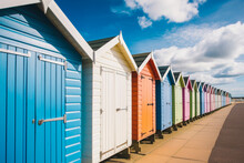 A Row Of Colorful Beach Huts With A Blue Sky In The Background