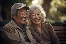 Generative AI Image Of Portrait Of Smiling Elderly Asian Couple Sitting On Bench In Park While Female Looking At Camera And Male Looking Away Against Blurred Green Trees
