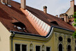 Copper flashing detail on sloped brown clay tile roof and dormer. oval rococo style window. decorated stucco elevation. old architecture concept and construction. travel and tourism. metal flashing