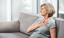 Heart Attack, Chest And Senior Woman With Pain In Her Home Living Room Or Couch With An Emergency Or Crisis On A Sofa. Asthma, Medical And Sick Elderly Person With Discomfort Due To Illness