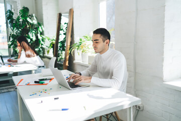 Wall Mural - Focused young man working on laptop in office