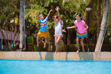 Kids jump into swimming pool. Summer water fun.