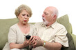 © Designpics - A senior couple fighting over the television remote control.  White background.