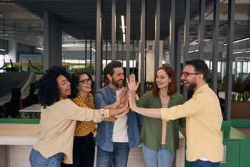 Group of happy startup business people giving high five in modern office