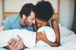 Happy interracial couple, bed and laughing in relax for intimate morning, bonding or relationship at home. Man and woman smiling with laugh in joyful happiness or relaxing weekend together in bedroom