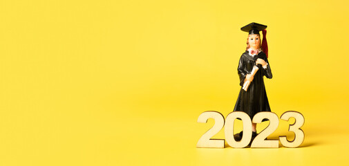 Wall Mural - Class of 2023 concept. Wooden number 2023 with graduate statuette on color background