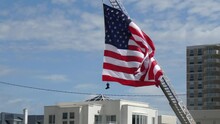 American Flag Seen Blowing In The Wind Hanging From A Fire Truck Ladder With Fireman's Boots Hanging From The Flag As A Weight.