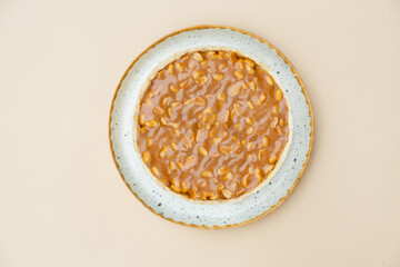 Cheesecake with nuts on round plate top view on beige background