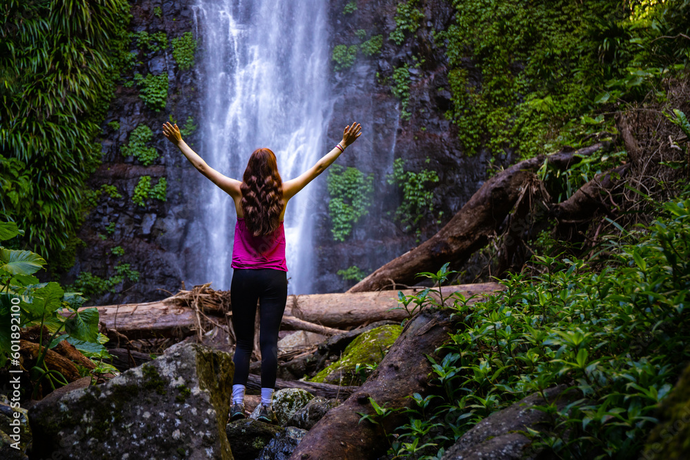long haired hiker girl standing in frong of large tropical waterfall in ...