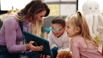 Poster - Woman with boy and girl having lesson using touchpad at kindergarten