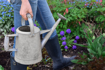 Closeup woman carrying waternig can in a garden