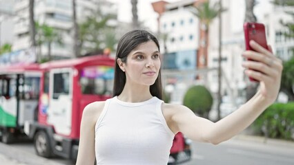 Wall Mural - Young beautiful hispanic woman smiling confident making selfie by the smartphone at street