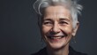 © Rudsaphon - Portrait of a beautiful senior woman smiling at the camera on a gray background.Generative Ai
