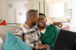 © Wavebreak Media - African american romantic gay couple looking at each other while watching movie over laptop on sofa