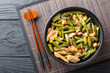 © FomaA - Delicious fried chicken fillet with asparagus and sesame seeds in soy sauce close-up in a bowl on the table. Horizontal top view from above