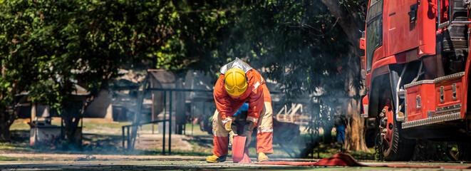 Wall Mural - Panorama view of firefighter rolled up the hose the sound of the sturdy fabric being folded echoed through the air a testament to the completion of their rescue mission.