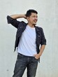 © Igunt - Cool modern young hipster man with a stylish hairstyle in a white T-shirt puts on a vintage black denim jacket. Attractive urban guy posing near a white wall. Fashionable spring menswear.
