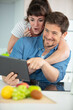 © auremar - couple using digital tablet while cooking