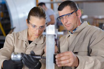 Wall Mural - male and female workers using air tool in workshop