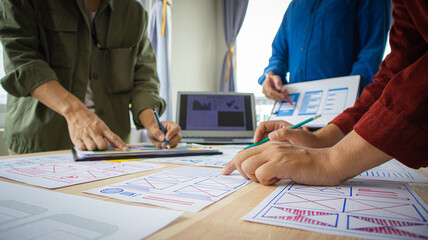 Close-up ux developers and ui designers use augmented reality to brainstorm on mobile app interface wireframe designs on modern office desks. Creative digital development office