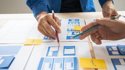 Close-up ux developers and ui designers use augmented reality to brainstorm on mobile app interface wireframe designs on modern office desks. Creative digital development office