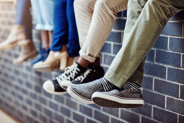 Poster - Brick wall, student feet and friends outdoor on university campus together with sneakers. Relax, urban youth and foot at college with people legs ready for education, study and shoes while sitting