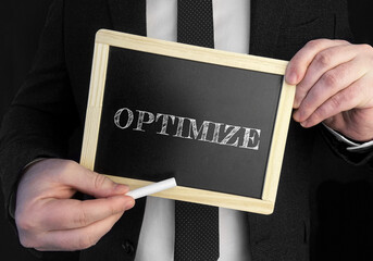 Poster - A businessman holds up a chalkboard with text Optimize