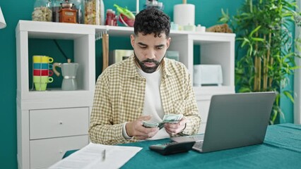 Sticker - Young hispanic man using laptop counting dollars at dinning room