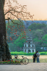 Wall Mural - Blooming bombax ceiba tree at Hoan Kiem lake. Turtle Tower (Thap Rua) on background