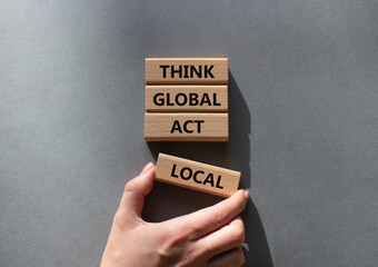 Think global act local symbol. Wooden blocks with words Think global act local . Beautiful grey background. Businessman hand. Business and Think global act local concept. Copy space.