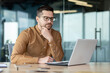 © Tetiana - Confused young male businessman sits in the office in front of a laptop and looks thoughtfully at the screen, concentrates on a new project, solves a problem