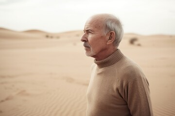 Wall Mural - Portrait of an elderly man standing in the desert and looking away