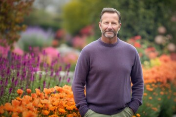 Poster - Environmental portrait photography of a pleased man in his 40s wearing a cozy sweater against a colorful flower garden background. Generative AI