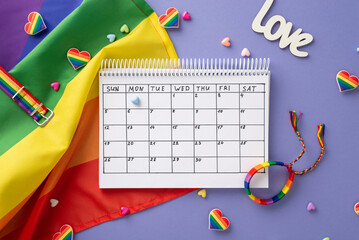 The concept of celebrating diversity and inclusivity is captured in this top-down view of pride-themed accessories, rainbow flag, calendar arranged on a lilac backdrop with space for personalized note