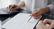 © rogerphoto - Woman accountant using a calculator and laptop computer while counting taxes for a client. Business audit concepts