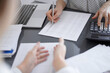 © rogerphoto - Woman accountant using a calculator and laptop computer while counting taxes with a client or colleague. Business audit team