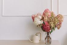 Vase Of Hydrangea Flowers On A Sideboard With A Watering Can