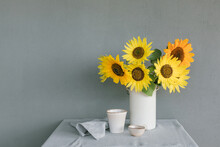 Bunch Of Sunflowers In A Vase On A Table With Ceramic Crockery And A Napkin