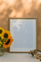 Vase Filled With Sunflowers Next To A Blank Picture Frame