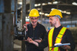 © VStudio - Two operators inspecting machines in industrial factory, holding documents and tablet for check, background in industrial warehouse., middle-aged male worker, Caucasian.