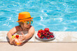 Child in swimming pool playing in summer water. Vacation and traveling with kids. Summer fruits for children.